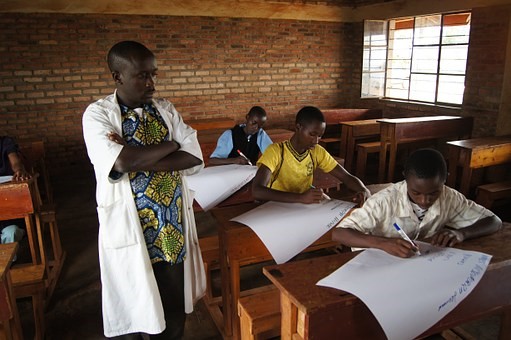 Image of an teacher overlooking student’s assignment in a classroom in Africa