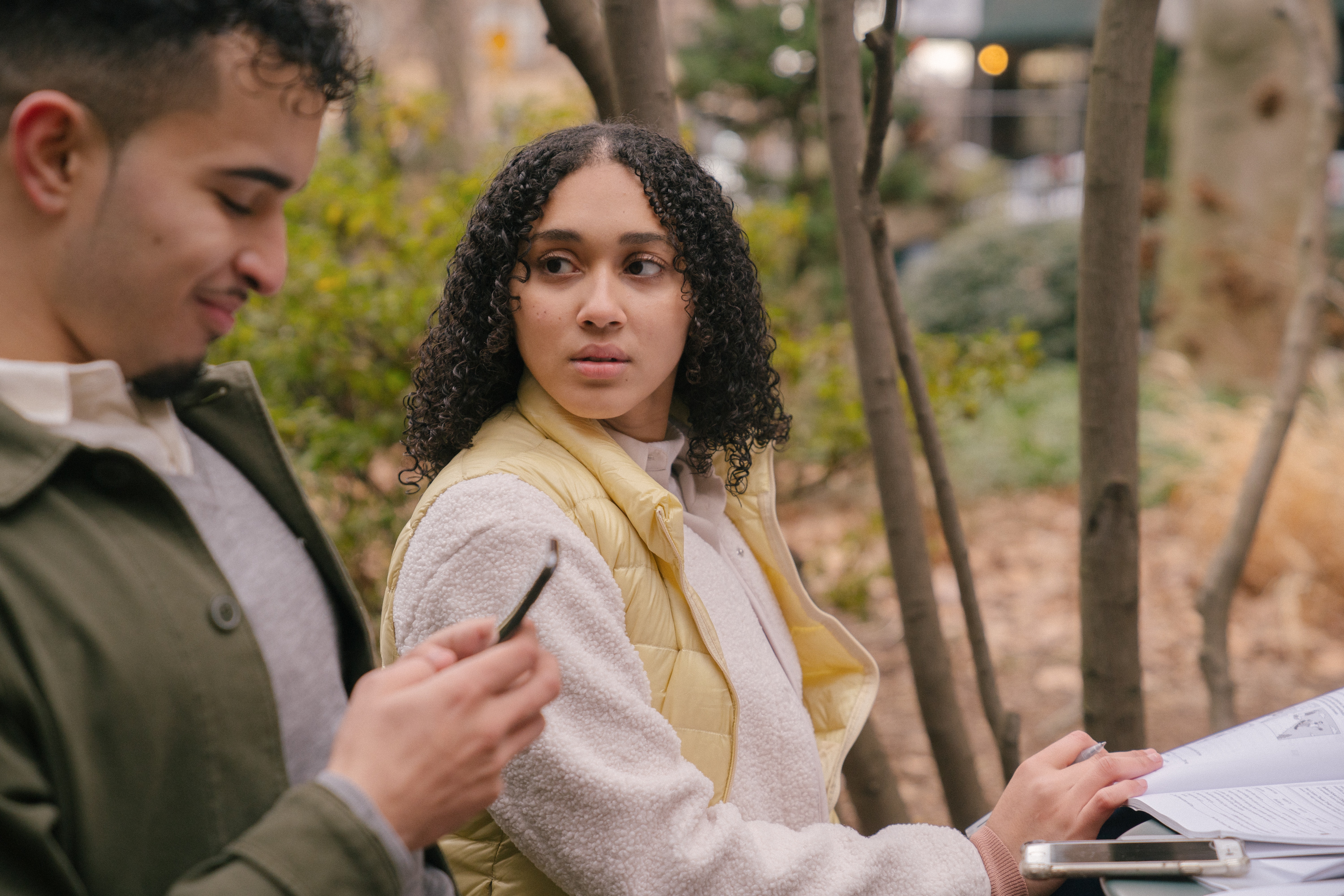 couple sitting on a park bench while man looks at his phone